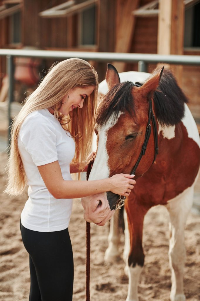 Taking care of animal. Happy woman with her horse on the ranch at daytime